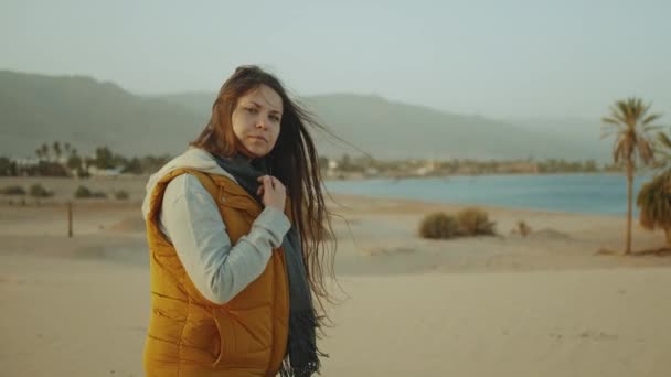 Kız sahilde yürüyüp Horizon 'u araştırıyor. Kadının sırtından kumsal ve mavi deniz manzarası, yavaş çekim, 4k — Stok video