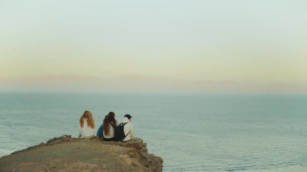 Grupo de amigos relajándose en la cima de una montaña al atardecer y disfrutando de la vista al mar - amistad, juventud, cámara lenta, 4k — Vídeos de Stock