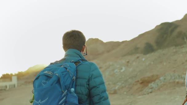 Groupe de promenade touristique le long du canyon rocheux dans le désert chaud, les touristes prennent des photos et s'amusent. Fond des montagnes du désert, Égypte, Sinaï, ralenti, 4k — Video