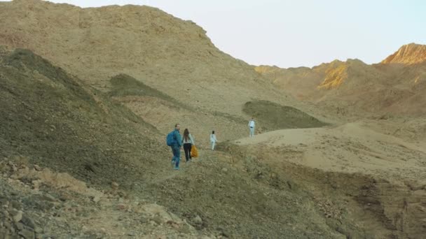 Gruppo di turisti a piedi lungo il canyon roccioso nel deserto caldo, i turisti scattare foto e divertirsi. Sullo sfondo delle montagne del deserto, Egitto, Sinai, rallentatore, 4k — Video Stock