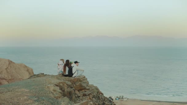 Grupo de amigos relaxando no topo de uma montanha ao pôr do sol e desfrutando de vista mar - amizade, juventude, câmera lenta, 4k — Vídeo de Stock