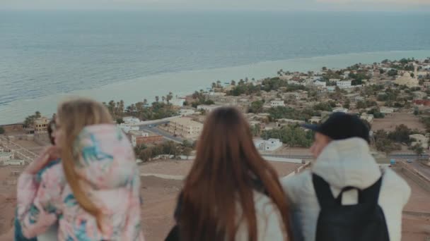 Grupa przyjaciół relaksujących się na szczycie góry na zachodzie słońca i cieszących się widokiem na morze - przyjaźń, młodzież, zwolnione tempo, 4k — Wideo stockowe