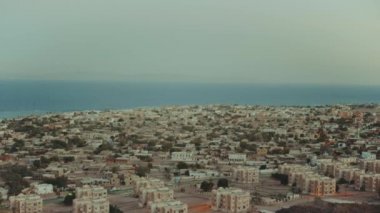 Mısır 'da gün batımı Sina dağları ve ufukta mavi deniz, dağların tepesinden küçük köye güzel bir manzara, dağlar zirveler, yavaş çekim, 4k
