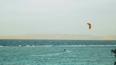 Dahab Mısır 'da temiz suda sörf yapan uçurtma. Arka planda dağlar olan mavi suyu keşfetmek ve rüzgar sörfü ve uçurtma sörfü, yavaş çekim, 4k