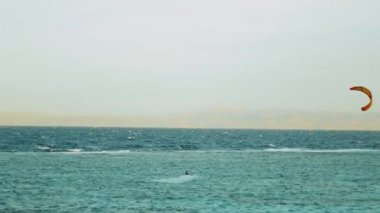 Dahab Mısır 'da temiz suda sörf yapan uçurtma. Arka planda dağlar olan mavi suyu keşfetmek ve rüzgar sörfü ve uçurtma sörfü, yavaş çekim, 4k