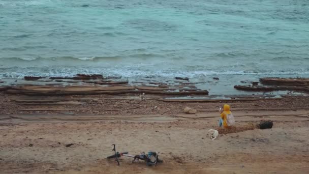 Mujer bonita con perro Labrador Retriever en la playa costera pedregosa cerca del mar, las olas se rompen en la orilla, Egipto Sinaí montaña en el fondo, cámara lenta, 4k — Vídeos de Stock
