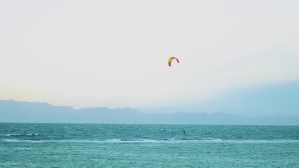 Cometa surfeando en aguas cristalinas en Dahab Egipto. Explorando el agua azul con montañas en el fondo y la gente windsurf y kitesurf, cámara lenta, 4k — Vídeos de Stock