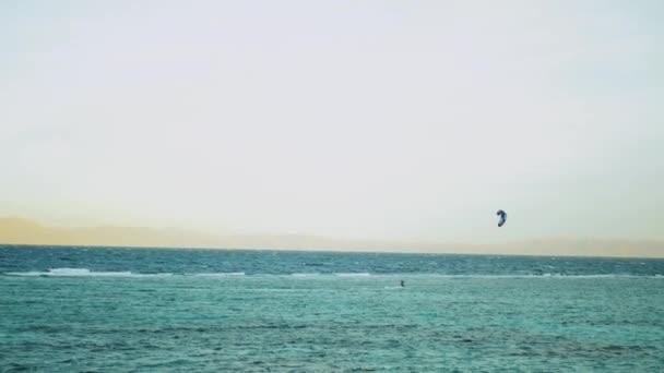 Cometa surfeando en aguas cristalinas en Dahab Egipto. Explorando el agua azul con montañas en el fondo y la gente windsurf y kitesurf, cámara lenta, 4k — Vídeos de Stock