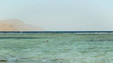 Güzel mavi deniz manzarası ve berrak gökyüzü, denizdeki dalgalar ve ufuktaki dağlar, Mısır, Dahab, yavaş çekim, 4k