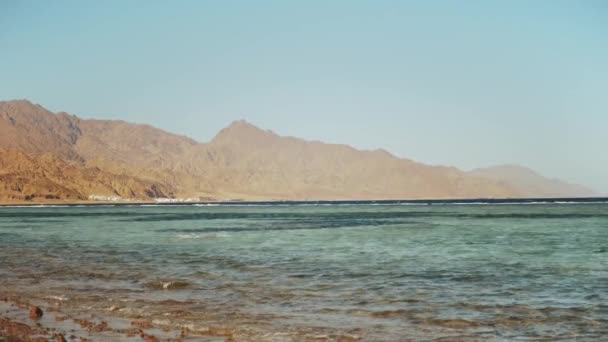 Mennesket snorkler i rødt hav, vakkert landskap i blått hav og klar himmel, bølger i havet og fjell i horisonten Egypt, Dahab, langsom bevegelse, 4k – stockvideo