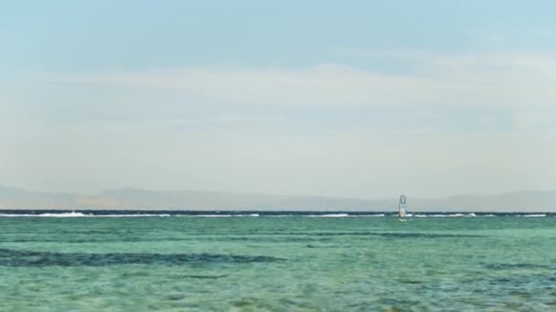 Windsurf en aguas cristalinas en Dahab Egipto. Explorando el agua azul con montañas en el fondo y la gente windsurf y kitesurf, cámara lenta, 4k — Vídeos de Stock