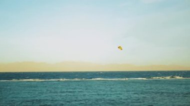 Dahab Mısır 'da temiz suda sörf yapan uçurtma. Arka planda dağlar olan mavi suyu keşfetmek ve rüzgar sörfü ve uçurtma sörfü, yavaş çekim, 4k