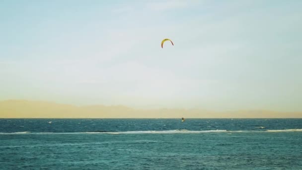Vliegersurfen in prachtig helder water in Dahab Egypte. Het verkennen van het blauwe water met bergen op de achtergrond en mensen windsurfen en kitesurfen, slow motion, 4k — Stockvideo