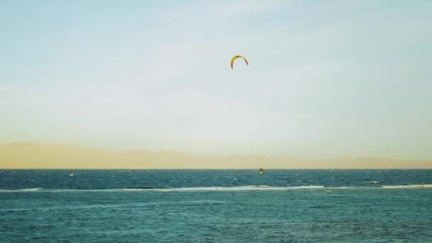 Latawce surfing w pięknej czystej wodzie w Dahab Egipt. Zwiedzanie błękitnej wody z górami w tle i ludzi windsurfing i kitesurfing, zwolnione tempo, 4k — Wideo stockowe