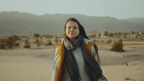 Nő hosszú haj séta sivatagban, tenger és hegyek a háttérben, lassított felvétel. — Stock videók