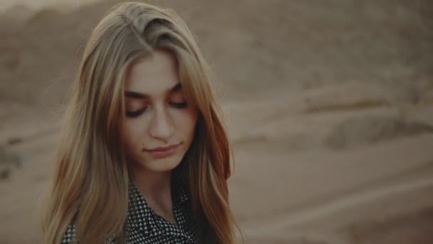 Retrato de mulher loira bonita com olhos fechados no pôr do sol. Jovem feliz em pé em uma montanha do deserto, paisagem do pôr do sol, câmera lenta, hd completo — Vídeo de Stock