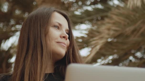 Студентка или фрилансер, работающая на ноутбуке, женщина, сидящая на балконе с видом на ладонь и море, быстрое видео, замедленная съемка, полная занятость. — стоковое видео