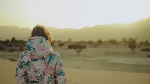 Mulher loira bonita andar ao pôr do sol no deserto. Feminino passando pelo deserto, dunas, close-up, câmera lenta, hd completo — Vídeo de Stock