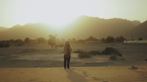 Una donna cammina nel deserto e guarda dentro Horizon. Vista delle montagne desertiche e del mare blu dal retro della femmina, rallentatore, hd completo — Video Stock