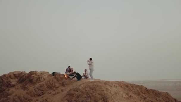 Grupo de personas que se relajan en la cima de una montaña en la puesta del sol, sentado cerca de la hoguera, disfrutando de su tiempo - amistad, juventud, cámara lenta, hd completa — Vídeo de stock