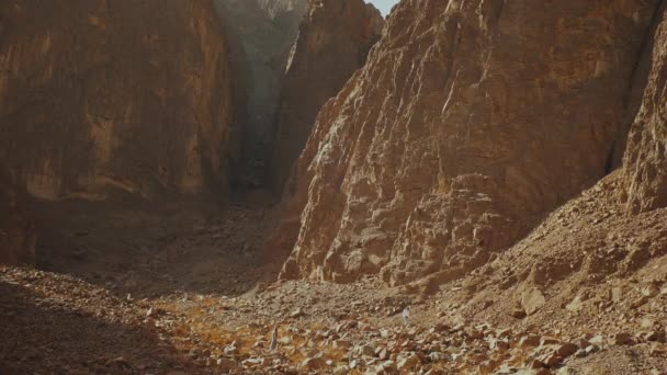 Homem turístico caminhar ao longo do desfiladeiro de rocha no deserto quente. Desert rocks fundo, Egito, Sinai, câmera lenta, hd completo — Vídeo de Stock