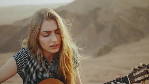 Vrouw spelen gitaar en zingen in woestijn landschappen, woestijn bergen achtergrond, slow motion, full hd — Stockvideo