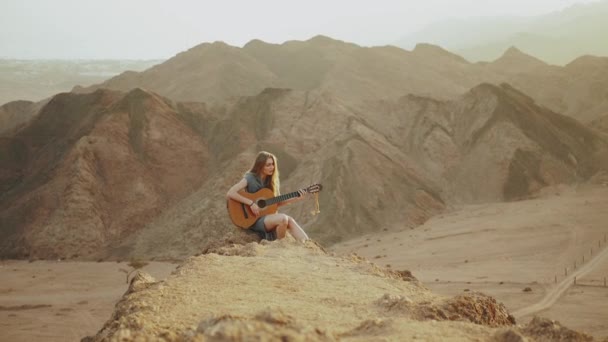 Mulher tocando guitarra e cantando em paisagens desérticas, deserto montanhas fundo, câmera lenta, hd completo — Vídeo de Stock