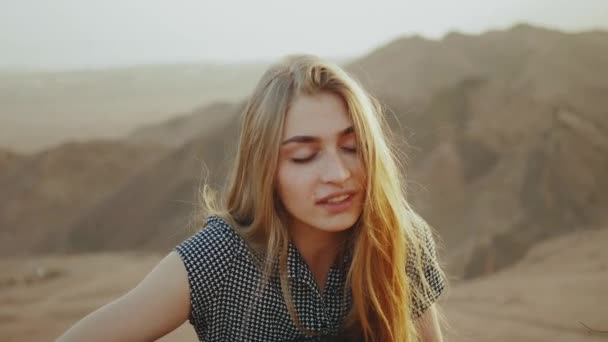 Femme jouant de la guitare et chantant dans des paysages désertiques, fond de montagnes désertiques, ralenti, full hd — Video