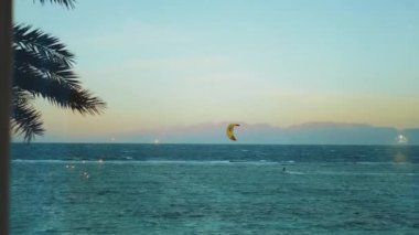 Dahab Mısır 'da temiz suda sörf yapan uçurtma. Arka planda dağlar olan mavi suyu keşfetmek ve insanlar rüzgar sörfü ve uçurtma sörfü, yavaş çekim, tam hd