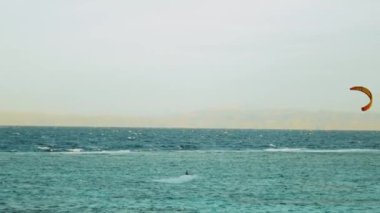 Dahab Mısır 'da temiz suda sörf yapan uçurtma. Arka planda dağlar olan mavi suyu keşfetmek ve insanlar rüzgar sörfü ve uçurtma sörfü, yavaş çekim, tam hd
