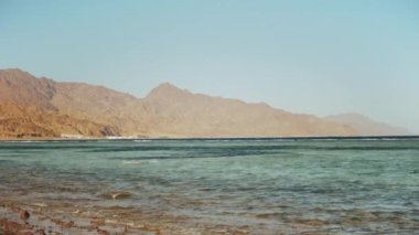 Kızıl denizde şnorkelle yüzen adam, güzel mavi deniz manzarası ve berrak gökyüzü, denizdeki dalgalar ve ufuktaki dağlar, Mısır, Dahab, yavaş çekim, tam hd