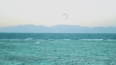 Dahab Mısır 'da temiz suda sörf yapan uçurtma. Arka planda dağlar olan mavi suyu keşfetmek ve insanlar rüzgar sörfü ve uçurtma sörfü, yavaş çekim, tam hd