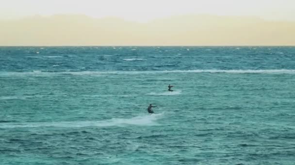 Vliegersurfen in prachtig helder water in Dahab Egypte. Het verkennen van het blauwe water met bergen op de achtergrond en mensen windsurfen en kitesurfen, slow motion, full hd — Stockvideo