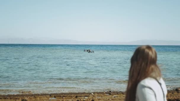 Женщина смотрит, как группа аквалангистов идут нырять в красном море, солнечный день и чистая вода в Дахабе, Египет, замедленное движение, полный hd — стоковое видео