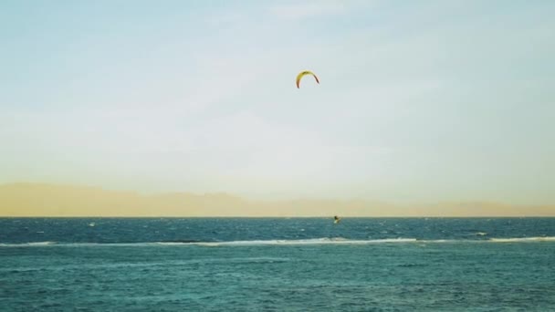 Kite surfing in beautiful clear water in Dahab Egypt. Exploring the blue water with mountains in the background and people windsurfing and kite surfing, slow motion, full hd — Stock Video