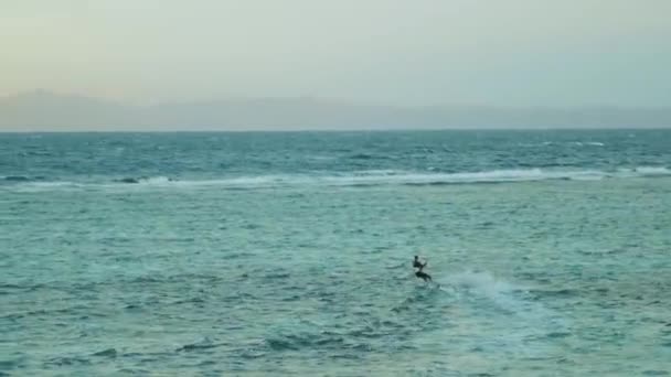 Cometa surfeando en aguas cristalinas en Dahab Egipto. Explorando el agua azul con montañas en el fondo y la gente windsurf y kitesurf, 4k — Vídeo de stock