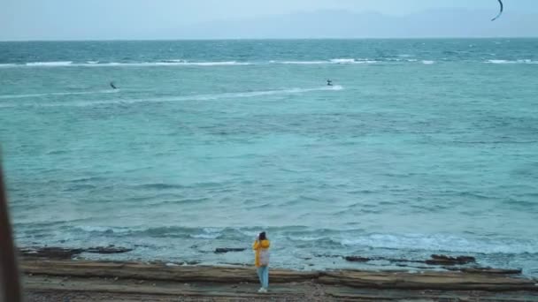 美丽的女人在海边的石滩上走着拍照，海浪冲破了海岸，背景是埃及西奈山，4k — 图库视频影像