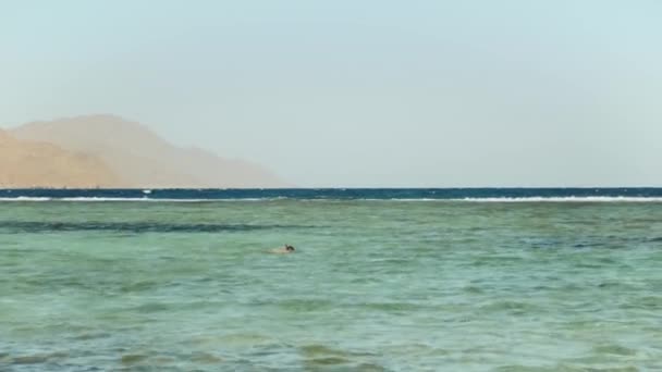 Homme plongée en apnée dans la mer rouge, Beau paysage de mer bleue et ciel clair, vagues dans la mer et les montagnes à l'horizon Egypte, Dahab, 4k — Video