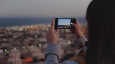 Akşamları akıllı telefondan denizin fotoğrafını çeken kadın dağın tepesinde durur ve Horizon 'a bakar.