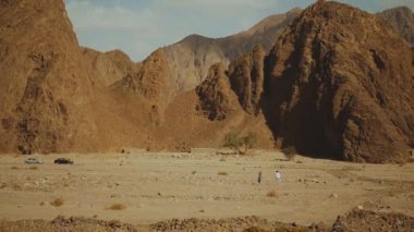 Bir grup turist sıcak çölde kaya kanyonu boyunca yürüyorlar. Çöl kayalıkları, Mısır, Sina, 4k