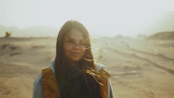 Portret van een mooie vrouw bij zonsondergang in de woestijn. Gelukkige jonge vrouw staat in de wind tegen Egypte woestijn zonsondergang landschap, 4k — Stockvideo