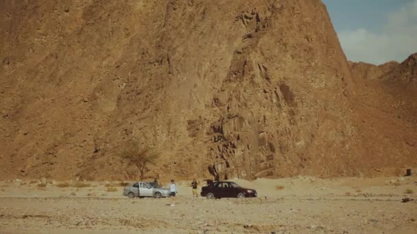 Egy csoport turista sétál a szikla kanyonban a forró sivatagban. Sivatagi sziklák háttér, Egyiptom, Sinai, 4k — Stock videók