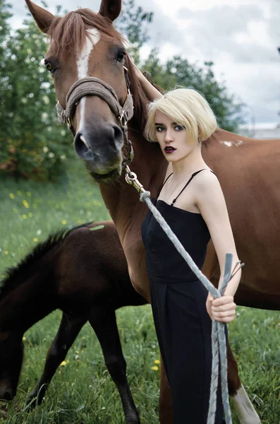 Beautiful blond girl walks with a horse — Stock Photo, Image