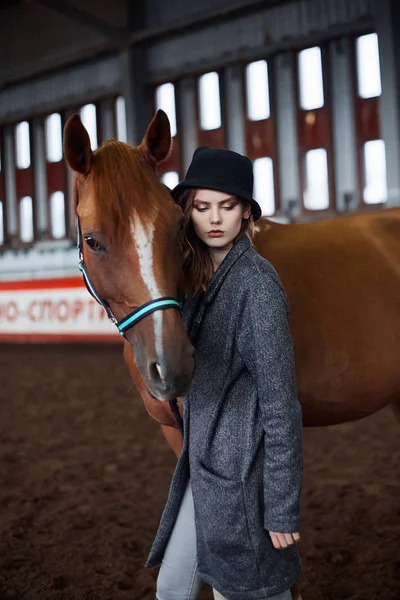 Красива дівчина в капелюсі, що йде з конем — стокове фото