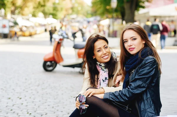 Dos chicas felices posando en la calle de la ciudad, cerca de un scooter —  Fotos de Stock