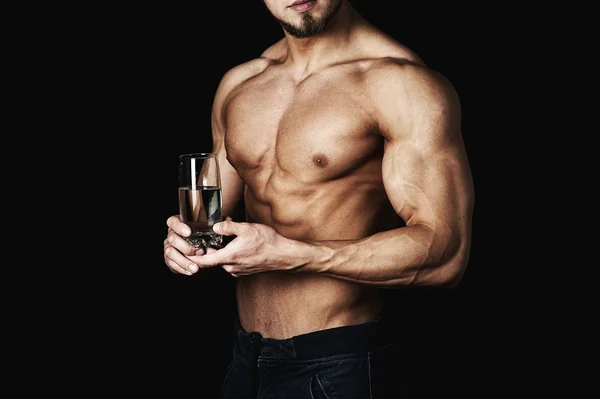 Joven sano inflado, sosteniendo un vaso de agua. Una forma de vida saludable. Sobre un fondo oscuro  . —  Fotos de Stock