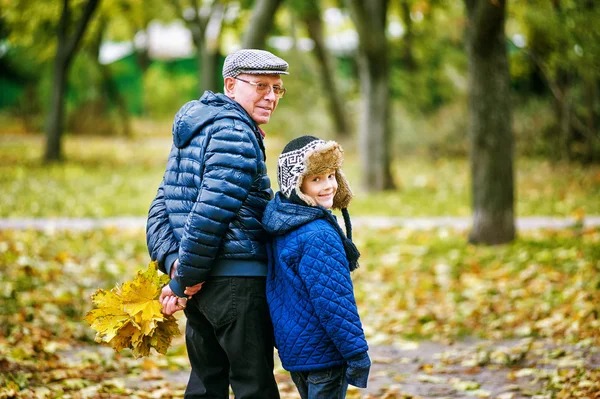 Grandfather walking with grandson playing in autumn Park — Stock Photo, Image