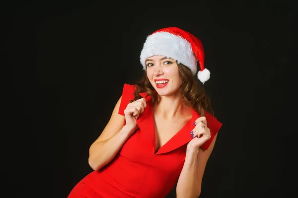 Mulher bonita em um vestido vermelho e chapéu de Papai Noel em um fundo preto — Fotografia de Stock