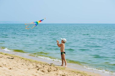 Dinlenme ve bir uçurtma ile sahilde oynarken küçük çocuk
