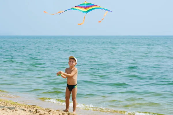 Kleiner Junge ruht sich aus und spielt am Strand mit einem Drachen — Stockfoto